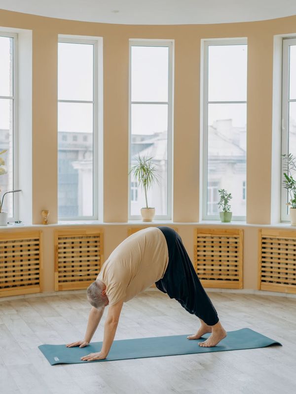 Man stretching on a yoga mat in a spacious, well-lit room.